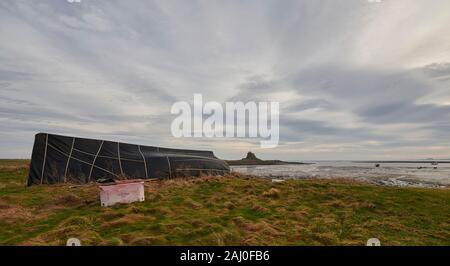 Alte Hering Boote umgedrehten und für die Speicherung auf Lindisfarne oder Heilige Insel auf der Northumbrian Küste von North Eastern England, UK, GB verwendet. Stockfoto