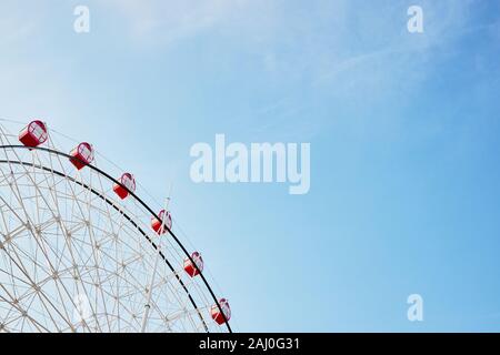 Riesenrad mit leuchtend roten Ständen auf Hintergrund des ruhigen klaren blauen Himmel als Symbol der Freude Erholung Entspannung Spaß und gute Zeit mit kopieren. Stockfoto