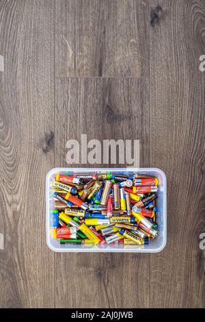 Adelaide, Australien - 7. Juli 2019: Zusammenstellung der verwendeten Haushalt AA- und AAA-Akkus in Kunststoff Behälter für die Entsorgung auf Holz zurück gesammelt Stockfoto