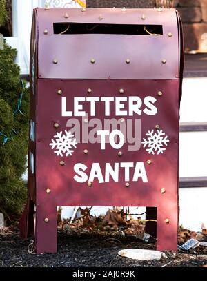 Nahaufnahme eines Urlaub Dekoration, dass es einen roten Briefkasten mit Buchstaben zu Santa geschrieben auf der Vorder- und Weihnachtsbeleuchtung. Stockfoto