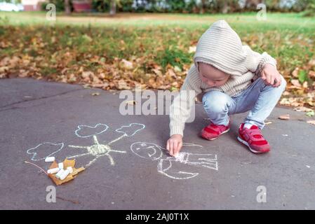 Kleinen Jungen 3-5 Jahre, zieht mit Buntstiften auf Asphalt zeichnen, kreative und Idee Art. Ruhende Wochenende, Spaziergang im Herbst Park. Freier Speicherplatz zum Kopieren von Text Stockfoto