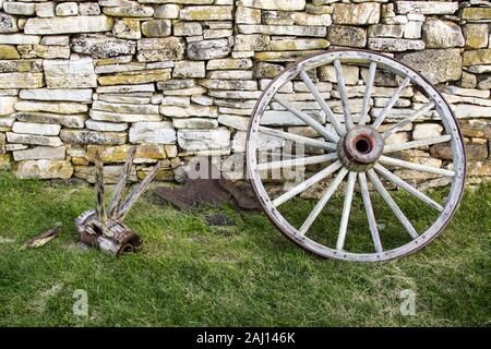 Wagon Wheel. Hölzernen Wagen Rad gegen eine alte Stein Wand lehnt. Stockfoto