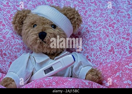 Spielzeug Teddybären krank im Bett liegt, Bettwäsche Rot Weiß mit Blumenmuster Stockfoto