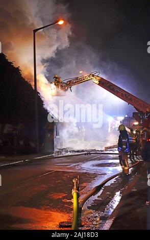 Fiiremen Kampf gegen ein Feuer im Dachstuhl eines Hauses in der Nacht aus dem Boden und aus einem Fire Company Kran Stockfoto