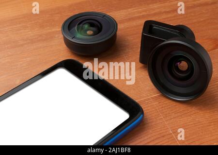 Leerer Bildschirm Smartphone auf Holztisch mit einigen Add-on Linsen Stockfoto