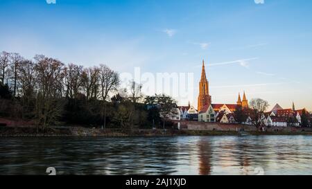 Deutschland, Baden-Württemberg, Ulm City Skyline, Stadtbild und minster Kathedrale hinter dem Wasser der Donau in romantischen warmen orange Sonnenuntergang Licht Stockfoto
