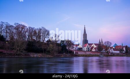 Deutschland, Baden-Württemberg, Ulm City Skyline, Stadtbild und minster Kathedrale hinter dem Wasser der Donau in der schönen violetten Nachleuchten Licht nach Sonnenuntergang Stockfoto