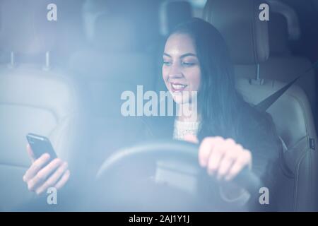 Schöne junge tausendjährigen Frau texting und Fahren Stockfoto