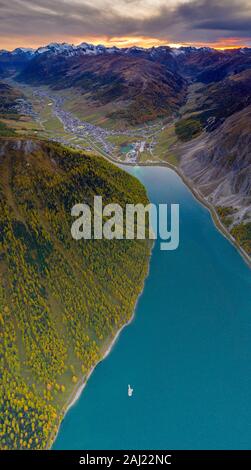 Antenne Panoramablick von Sonnenuntergang über Livigno und Lärchen entlang der See im Herbst, Sondrio Provinz, Valtellina, Lombardei, Italien, Europa Stockfoto