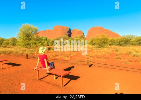 Touristische Frau entspannend auf einer Bank bewundern Felsformationen von Kata Tjuta Sunset Viewing Area, Uluru-Kata Tjuta National Park, Australien Stockfoto