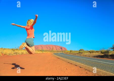 Touristische Frau am Uluru (Ayers Rock) im Uluru-Kata Tjuta National Park, UNESCO, Northern Territory springen, Zentral Australien Stockfoto