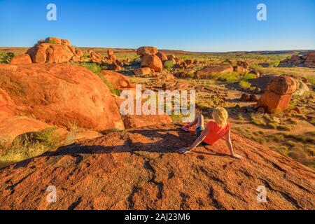 Touristische Frau auf eine Ansicht von oben Karlu Karlu (Devils Marbles) Erhaltung an Felsformationen bei Sonnenuntergang, Outback Suche Finden, Australien Stockfoto