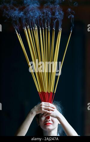 Junge chinesische betende Frau mit großen Räucherstäbchen in ihren Händen, Ha Chuong Hoi Quan Pagode, Ho Chi Minh City, Vietnam, Indochina, Asien Stockfoto