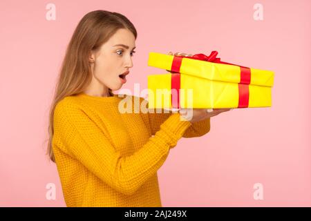 Porträt der schöne Rote Haare Mädchen in Pullover peeking mit Interesse in Geschenkbox, Auspacken zu Weihnachten oder zum Geburtstag überraschen, mit einer Stockfoto