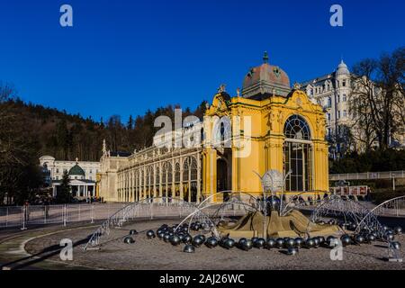 In Marianske Lazne, Tschechische Republik - 1. Januar 2020: Blick auf gelbe Gebäude der Kolonnade aus Gusseisen mit der Singning Wasser Brunnen vor. Stockfoto