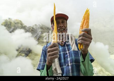 Ijen, Indonesien. 11 Dez, 2019. Ein indonesischer Schwefel Bergmann zeigt einige der Materialien, die er von der Erde in den Ijen Vulkans extrahiert. Die Ijen Vulkan ist einer der wenigen Orte, an denen Schwefel noch ohne Maschinen abgebaut ist, den Krater des Vulkans hat einen aktiven Schlot produziert, dass elementarer Schwefel. Atmung in den Schwefel Gas kann langfristige gesundheitliche Auswirkungen verursachen, aber trotzdem gibt es keinen Mangel an lokalen Bergleute riskieren alles, was ein gutes Gehalt zu verdienen ist, Bergarbeiter, einem durchschnittlichen Einkommen dreimal höher als die der lokalen Gehalt. Reiner Schwefel ist im Haushalt Reinigung verwendet Prod Stockfoto