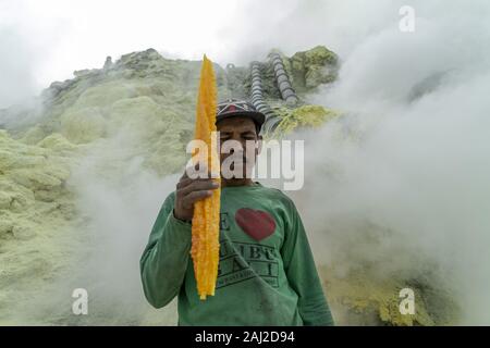 Dezember 11, 2019, Ijen, Indonesien: Ein indonesischer Bergmann mit einem großen Stück von Schwefel aus der Mine in der Ijen Vulkans.. Die Ijen Vulkan ist einer der wenigen Orte, an denen Schwefel noch ohne Maschinen abgebaut ist, den Krater des Vulkans hat einen aktiven Schlot produziert, dass elementarer Schwefel. Atmung in den Schwefel Gas kann langfristige gesundheitliche Auswirkungen verursachen, aber trotzdem gibt es keinen Mangel an lokalen Bergleute riskieren alles, was ein gutes Gehalt zu verdienen ist, Bergarbeiter, einem durchschnittlichen Einkommen dreimal höher als die der lokalen Gehalt. Reiner Schwefel ist im Haushalt Reinigung Produkte verwendet, Make up, explosiv Stockfoto