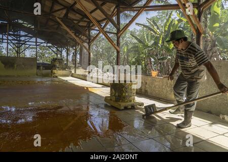 Banyuwangi, Indonesien. 10 Dez, 2019. Siedende Flüssigkeit Schwefel ist auf einem gefliesten Boden gegossen an einem Schwefel Verarbeitung Fabrik tief im Dschungel in der Nähe von Banyuwangi abkühlen. Die Ijen Vulkan ist einer der wenigen Orte, an denen Schwefel noch ohne Maschinen abgebaut ist, den Krater des Vulkans hat einen aktiven Schlot produziert, dass elementarer Schwefel. Atmung in den Schwefel Gas kann langfristige gesundheitliche Auswirkungen verursachen, aber trotzdem gibt es keinen Mangel an lokalen Bergleute riskieren alles, was ein gutes Gehalt zu verdienen ist, Bergarbeiter, einem durchschnittlichen Einkommen dreimal höher als die der lokalen Gehalt. Reine sulphu Stockfoto