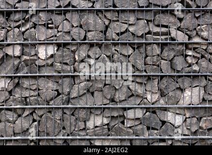 Trümmerstein in Stahlnetzwand. Texturhintergrund. Stockfoto