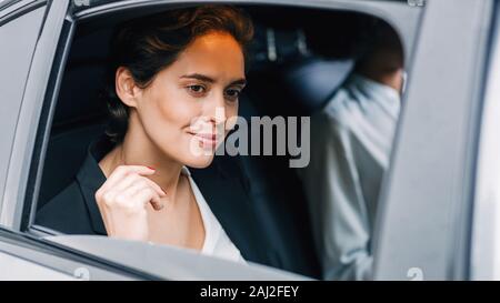 Schöne Geschäftsfrau Blick aus dem Fenster eines Taxis. Junge Frau, die mit dem Auto anreisen. Stockfoto