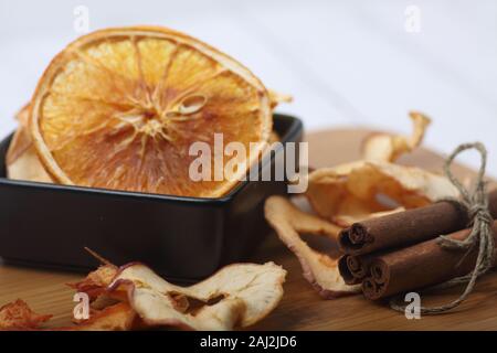 Eine Schale mit Obst Chips auf Holz Schneidebrett und ein Haufen von Zimtstangen auf Schneidebrett. Bild enthält Platz kopieren Stockfoto