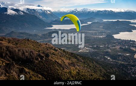 BARILOCHE, Argentinien, 19. JUNI 2019: Paragliding über Nahuel Huapi See und Berge von Bariloche in Argentinien, mit verschneiten Gipfeln im Hintergrund Stockfoto