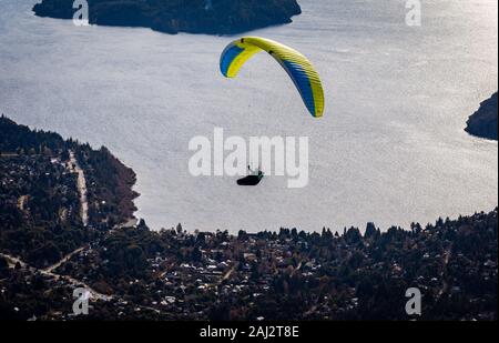 BARILOCHE, Argentinien, 19. JUNI 2019: Paragliding über See Nahuel Huapi und Stadtbild von Bariloche in Argentinien, mit verschneiten Gipfeln im Hintergrund Stockfoto