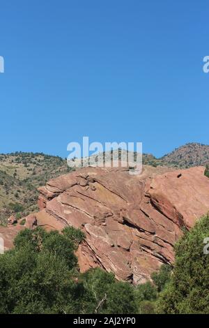 Große rote Felsformationen, ragt aus dem Boden, hinter Bäumen, auf der Trading Post Trail in Red Rocks State Park, Colorado, USA Stockfoto
