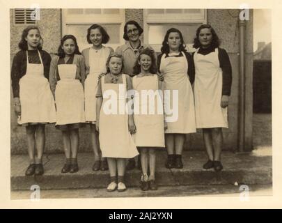 1950 die Schule Mädchen, Schürzen mit ihren inländischen Wissenschaft Lehrer, für ein Gruppenfoto außerhalb ihrer die High School oder Secondary School in Großbritannien posing Stockfoto