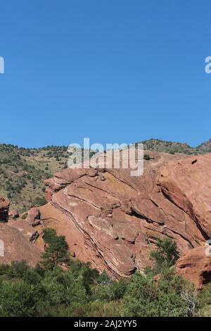 Große rote Felsformationen, ragt aus dem Boden, hinter Bäumen, auf der Trading Post Trail in Red Rocks State Park, Colorado, USA Stockfoto