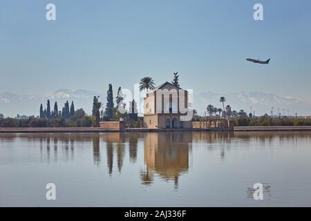 Der Menara mit weit entfernten Atlasgebirge und ein Flugzeug am Himmel Stockfoto