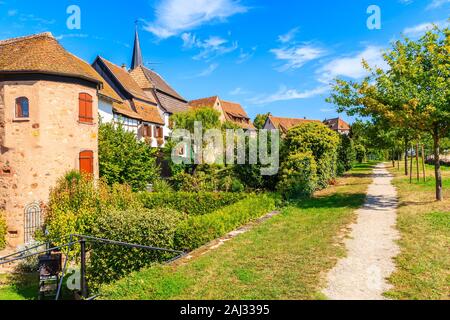 Pfad im Park und Blick auf die schöne traditionelle Häuser aus Steinen in Bergheim Stadt gebaut, Elsass, Frankreich Stockfoto