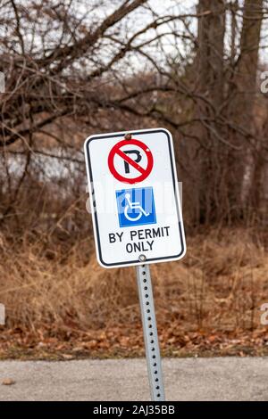 Burlington, Ontario, Kanada, 2. Januar 2020: Weißes Schild mit roten und blauen Symbolen, das auf einen behindertengerechten Parkplatz an einem Stadtpark hinweist Stockfoto