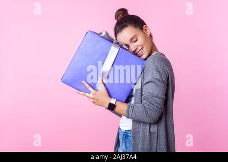 Lang ersehnte vorhanden. Portrait von erfreut Teenage brunette Mädchen mit bun Frisur in Freizeitkleidung, Geschenkbox, zufrieden zufrieden mit surp Stockfoto