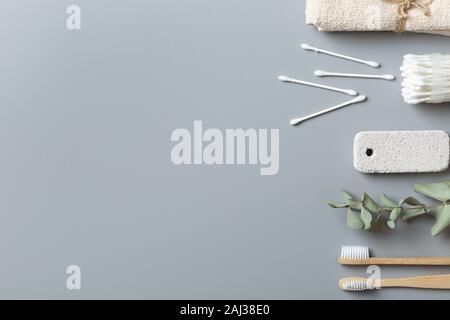 Ökologische Beauty Care Produkte auf grauem Hintergrund. Bambus Zahnbürste, Handtuch, Ohrhörer Stockfoto