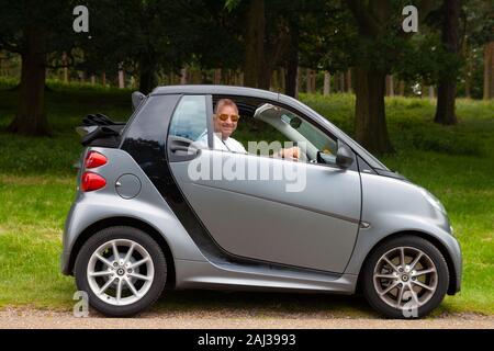 Lächelnd im mittleren Alter cool Mann in Smart Auto mit Verdeck Stockfoto