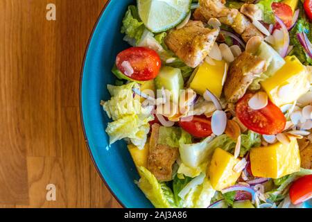 Blick von oben auf einen selbstgemachten Geflügelsalat mit Mango, Tomaten und frische Zwiebel Stockfoto