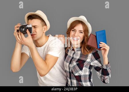 Junges Paar von stilvollen Reisende tragen Hüte Mann mit Kamera die Bilder konzentriert, während Frau mit Pässen, die Kamera lächelnd Ch Stockfoto