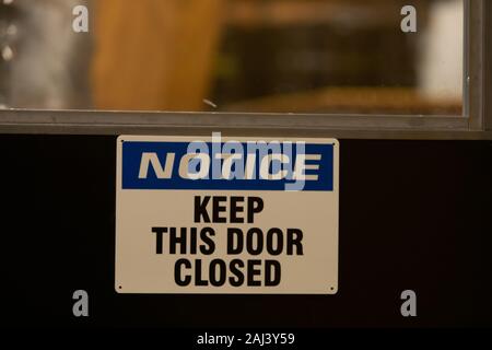 Beachten Sie, halten Sie die Tür geschlossen, text Informationen auf einem schwarzen Tür, industrielle Zimmer, die mit Warnung und Achtung Symbol, selektive konzentrieren und Ansicht schließen Stockfoto