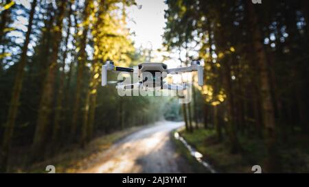 Graz, Österreich: 02.01.2020 - Close up Schießen eines DJI Quadcopter Drone Mavic Mini 249 g. Drohne fliegen im sonnigen Wald. DJI ist Marktführer in Drohnen Stockfoto