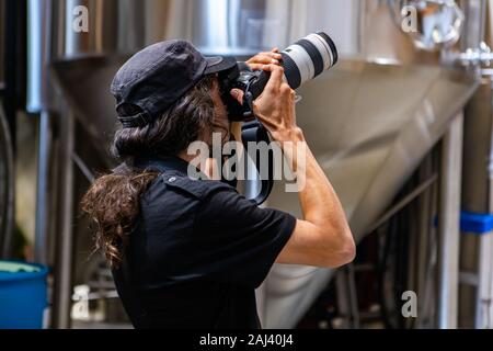 Kaukasische mann Fotograf Bilder aufnehmen mit DSLR-Kamera, Rückseite selektiven Fokus, gärtanks Schiffe Hintergrund Stockfoto