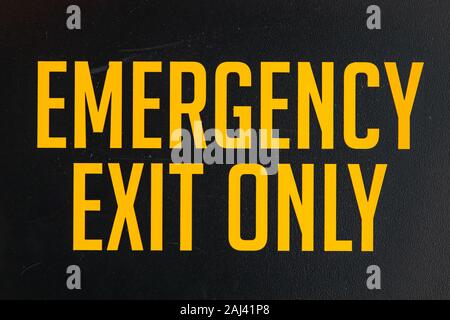 Notausgang nur Gelb Vinyl Sticker text Informationen auf einem schwarzen Tür, industrielle Zimmer Symbol, selektive konzentrieren und Ansicht schließen Stockfoto