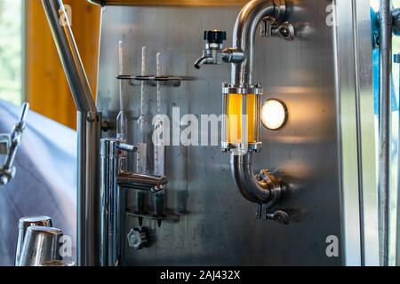 Bier Qualitätskontrolle Ausrüstung, Schauglas voller goldener Bier auf Rohr aus Edelstahl mit Licht und Schlauch bib Hahn Ventil für die Entnahme von Proben Stockfoto