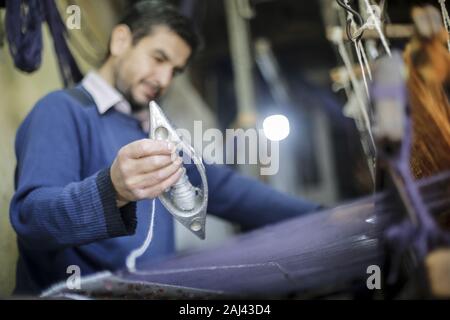 Gaza, Palästina. 2 Jan, 2020. Eine palästinensische Arbeiter webt Teppiche auf einem traditionellen Webstuhl an einem Teppich Fabrik in Gaza Stadt. Sprechen über alte Gaza, und was erscheint, sind die Bilder der Ton, bunte Glaswaren, Bambusmöbel und alten Rahmen Weben Webstühle helle Teppiche und Matten. Als solche Berufe sterben weltweit werden könnte, ist das Tempo ihrer sinkt zu schnell in Gaza, die sich aus der rund 500 Webstühlen, nur ein noch funktioniert. Credit: Mahmoud Issa/SOPA Images/ZUMA Draht/Alamy leben Nachrichten Stockfoto