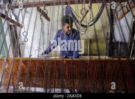 Gaza, Palästina. 2 Jan, 2020. Eine palästinensische Arbeiter webt Teppiche auf einem traditionellen Webstuhl an einem Teppich Fabrik in Gaza Stadt. Sprechen über alte Gaza, und was erscheint, sind die Bilder der Ton, bunte Glaswaren, Bambusmöbel und alten Rahmen Weben Webstühle helle Teppiche und Matten. Als solche Berufe sterben weltweit werden könnte, ist das Tempo ihrer sinkt zu schnell in Gaza, die sich aus der rund 500 Webstühlen, nur ein noch funktioniert. Credit: Mahmoud Issa/SOPA Images/ZUMA Draht/Alamy leben Nachrichten Stockfoto