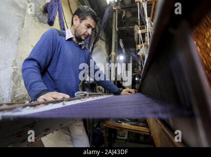 Gaza, Palästina. 2 Jan, 2020. Eine palästinensische Arbeiter webt Teppiche auf einem traditionellen Webstuhl an einem Teppich Fabrik in Gaza Stadt. Sprechen über alte Gaza, und was erscheint, sind die Bilder der Ton, bunte Glaswaren, Bambusmöbel und alten Rahmen Weben Webstühle helle Teppiche und Matten. Als solche Berufe sterben weltweit werden könnte, ist das Tempo ihrer sinkt zu schnell in Gaza, die sich aus der rund 500 Webstühlen, nur ein noch funktioniert. Credit: Mahmoud Issa/SOPA Images/ZUMA Draht/Alamy leben Nachrichten Stockfoto