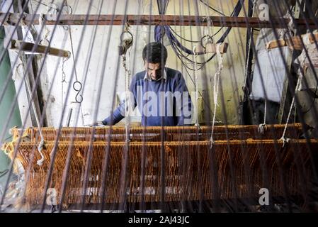 Gaza, Palästina. 2 Jan, 2020. Eine palästinensische Arbeiter webt Teppiche auf einem traditionellen Webstuhl an einem Teppich Fabrik in Gaza Stadt. Sprechen über alte Gaza, und was erscheint, sind die Bilder der Ton, bunte Glaswaren, Bambusmöbel und alten Rahmen Weben Webstühle helle Teppiche und Matten. Als solche Berufe sterben weltweit werden könnte, ist das Tempo ihrer sinkt zu schnell in Gaza, die sich aus der rund 500 Webstühlen, nur ein noch funktioniert. Credit: Mahmoud Issa/SOPA Images/ZUMA Draht/Alamy leben Nachrichten Stockfoto