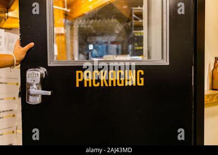 Verpackung gelb vinyl Sticker text Informationen anmelden, Hand auf offenen schwarzen Tür mit einem digitalen Lock, industrielle Zimmer Symbol Stockfoto