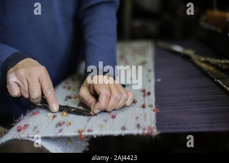 Gaza, Palästina. 2 Jan, 2020. Eine palästinensische Arbeiter webt Teppiche auf einem traditionellen Webstuhl an einem Teppich Fabrik in Gaza Stadt. Sprechen über alte Gaza, und was erscheint, sind die Bilder der Ton, bunte Glaswaren, Bambusmöbel und alten Rahmen Weben Webstühle helle Teppiche und Matten. Als solche Berufe sterben weltweit werden könnte, ist das Tempo ihrer sinkt zu schnell in Gaza, die sich aus der rund 500 Webstühlen, nur ein noch funktioniert. Credit: Mahmoud Issa/SOPA Images/ZUMA Draht/Alamy leben Nachrichten Stockfoto