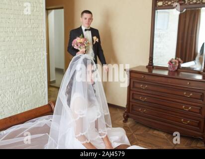 Die erste Sitzung der Braut und der Bräutigam am Hochzeitstag. Emotionen brautpaar vor der Trauung. Braut und Bräutigam sehen einander an, huggi Stockfoto